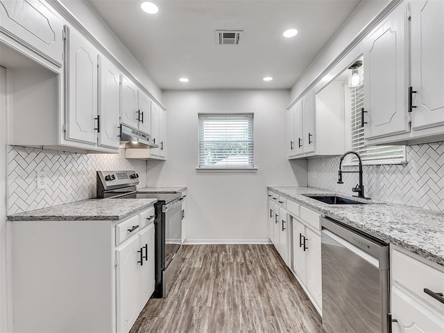 209 SW 6th St, Blanchard, OK 73010 - kitchen with appliances with stainless steel finishes, under cabinet range hood, decorative backsplash, white cabinets, and recessed lighting