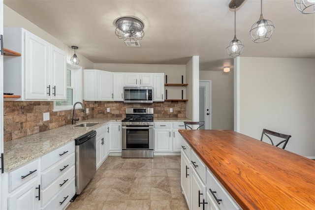822 W Broadway St, Okemah, OK 74859 - kitchen with butcher block countertops, open shelves, appliances with stainless steel finishes, tasteful backsplash, and white cabinets