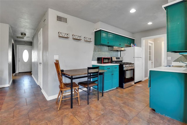 1001 NW 2nd St, Moore, OK 73160 - kitchen featuring stainless steel gas range, under cabinet range hood, green cabinetry, dark stone finish floors, and freestanding refrigerator