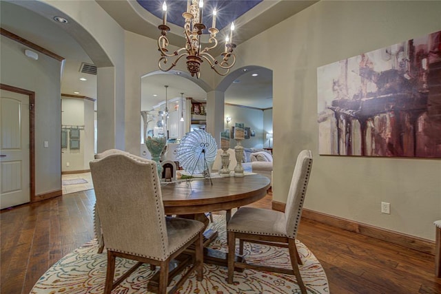 dining area featuring arched walkways, hardwood / wood-style flooring, and a chandelier