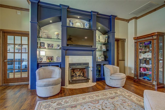 living room featuring crown molding, dark wood-type flooring, and a tiled fireplace
