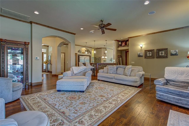 living area with crown molding, arched walkways, a ceiling fan, wood finished floors, and recessed lighting