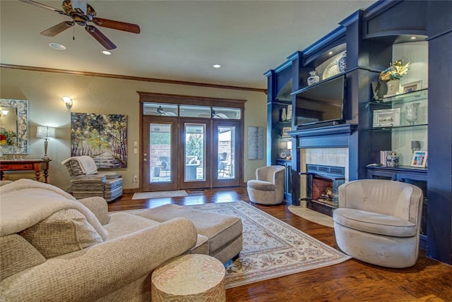 living area featuring ornamental molding, a fireplace, wood finished floors, a ceiling fan, and recessed lighting