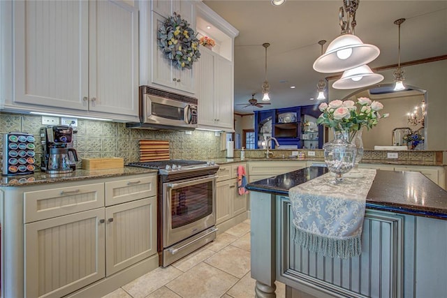 kitchen featuring stainless steel appliances, light tile patterned floors, tasteful backsplash, a ceiling fan, and ornamental molding