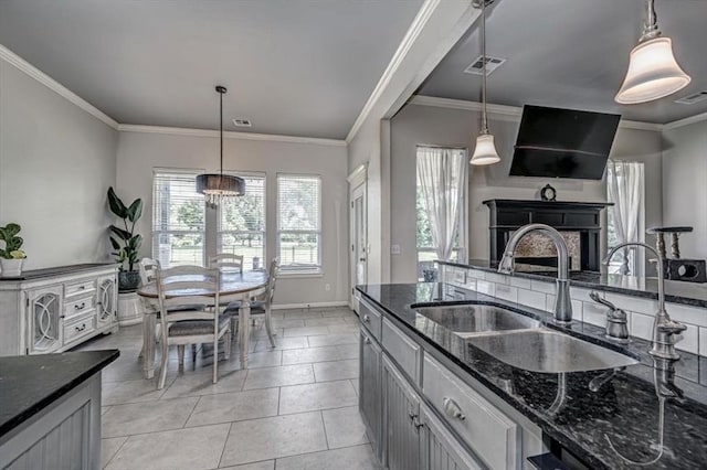 4450 Buffalo Hl, Guthrie, OK 73044 - kitchen with dark stone counters, a fireplace, crown molding, decorative light fixtures, and light tile patterned floors