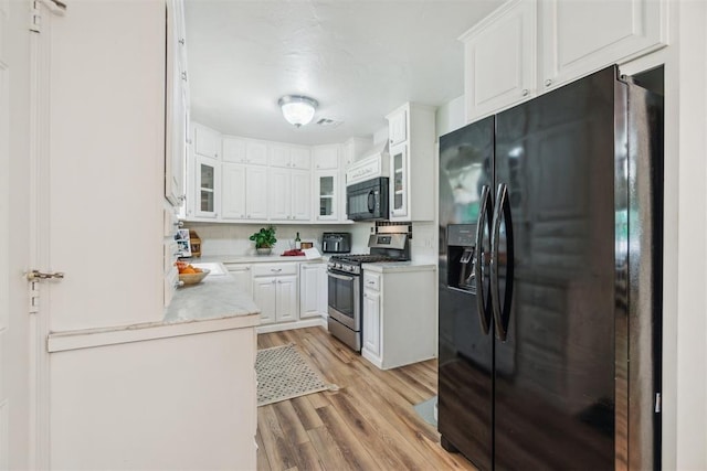 1726 Caddell Ln, Norman, OK 73069 - kitchen featuring black appliances, light wood-type flooring, light countertops, and white cabinets