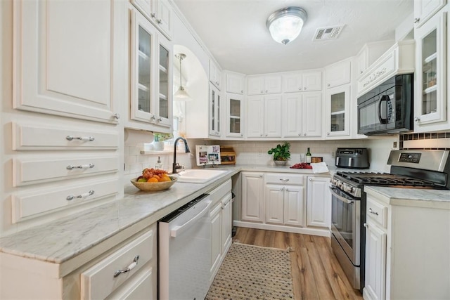 1726 Caddell Ln, Norman, OK 73069 - kitchen with stainless steel range with gas stovetop, dishwasher, black microwave, light wood-style flooring, and decorative backsplash