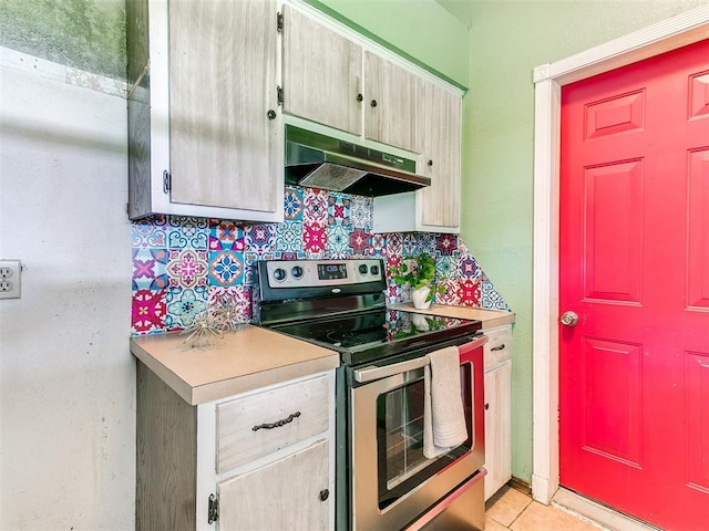 1916 Twin Tree Dr, Norman, OK 73071 - kitchen featuring stainless steel electric stove, under cabinet range hood, light countertops, backsplash, and light tile patterned flooring