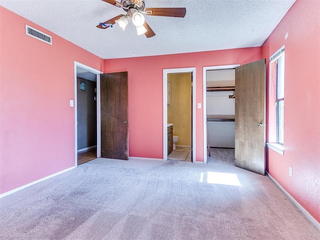 1916 Twin Tree Dr, Norman, OK 73071 - unfurnished bedroom featuring a textured ceiling, carpet floors, connected bathroom, ceiling fan, and a closet