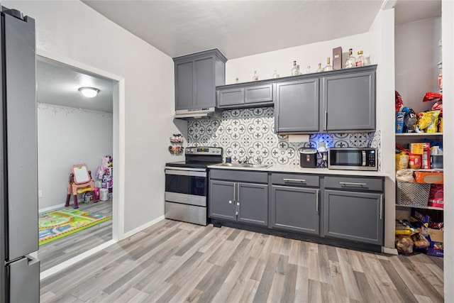 334 SE 24th St, Oklahoma City, OK 73129 - kitchen with stainless steel appliances, gray cabinets, light wood finished floors, under cabinet range hood, and decorative backsplash