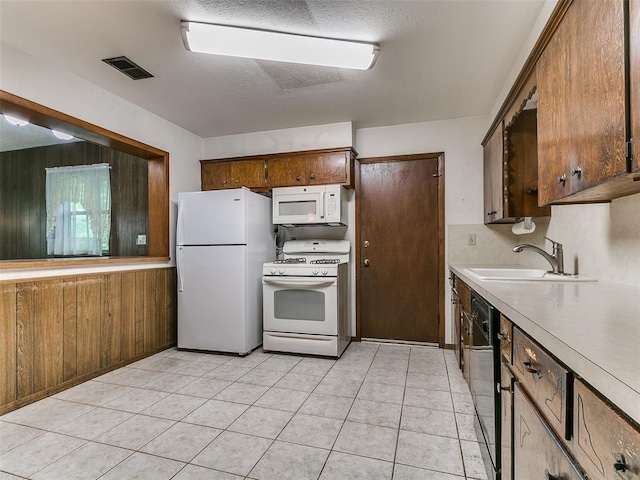 2120 N Divis Ave, Bethany, OK 73008 - kitchen with white appliances, light countertops, wooden walls, light tile patterned floors, and a textured ceiling