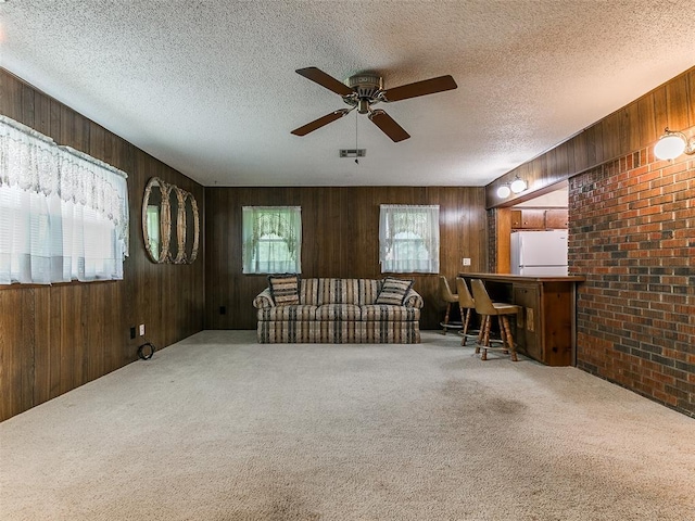 2120 N Divis Ave, Bethany, OK 73008 - carpeted living area featuring ceiling fan, wood walls, a textured ceiling, and brick wall