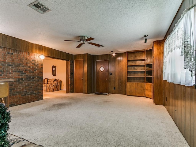 2120 N Divis Ave, Bethany, OK 73008 - unfurnished living room with wood walls, a ceiling fan, a textured ceiling, and carpet floors