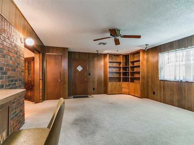 2120 N Divis Ave, Bethany, OK 73008 - unfurnished living room featuring wood walls, a ceiling fan, carpet floors, a textured ceiling, and built in features