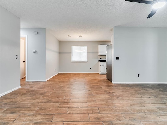1810 Spring Ave, Stroud, OK 74079 - unfurnished living room with ceiling fan, light wood-style flooring, and a textured ceiling