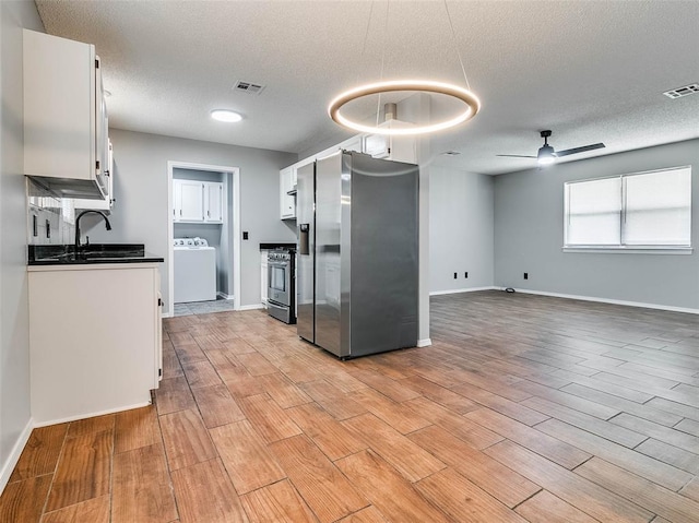 1810 Spring Ave, Stroud, OK 74079 - kitchen with washer / dryer, stainless steel appliances, dark countertops, white cabinetry, and a ceiling fan