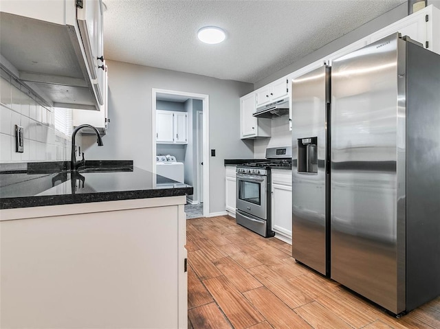 1810 Spring Ave, Stroud, OK 74079 - kitchen with stainless steel appliances, under cabinet range hood, light wood-type flooring, white cabinetry, and a textured ceiling