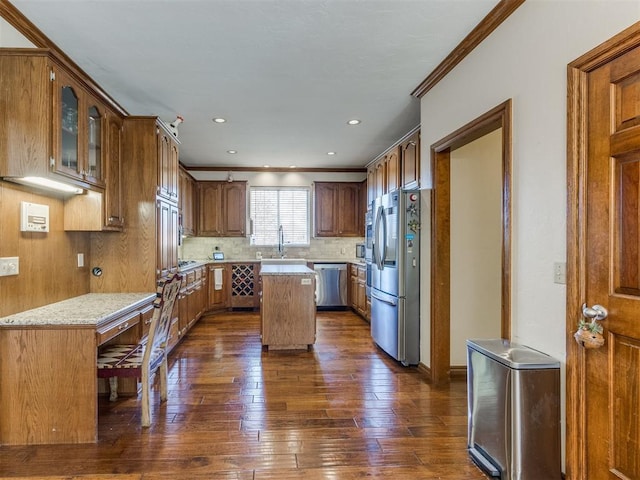 2404 Pawnee Xing, Edmond, OK 73034 - kitchen featuring appliances with stainless steel finishes, crown molding, dark wood-type flooring, a kitchen island, and backsplash