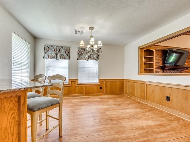 1917 Goldenrod Ln, Midwest City, OK 73130 - dining space with light wood finished floors, a chandelier, and wainscoting