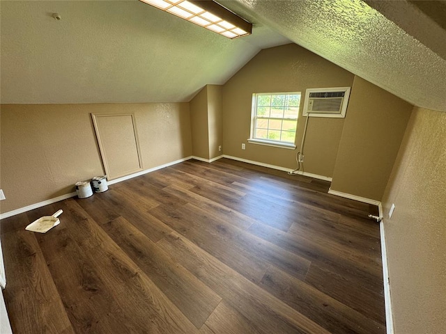 12237 N 359th Rd, Seminole, OK 74868 - bonus room with a wall mounted AC, dark wood finished floors, a textured ceiling, and vaulted ceiling