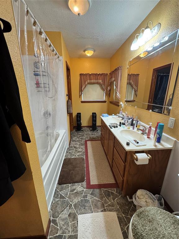 12237 N 359th Rd, Seminole, OK 74868 - full bathroom with a textured ceiling, vanity, and shower / tub combo