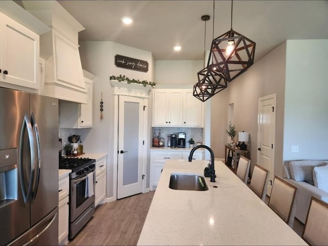 10812 NW 5th St, Yukon, OK 73099 - kitchen with appliances with stainless steel finishes, decorative backsplash, white cabinets, hanging light fixtures, and light wood-style flooring