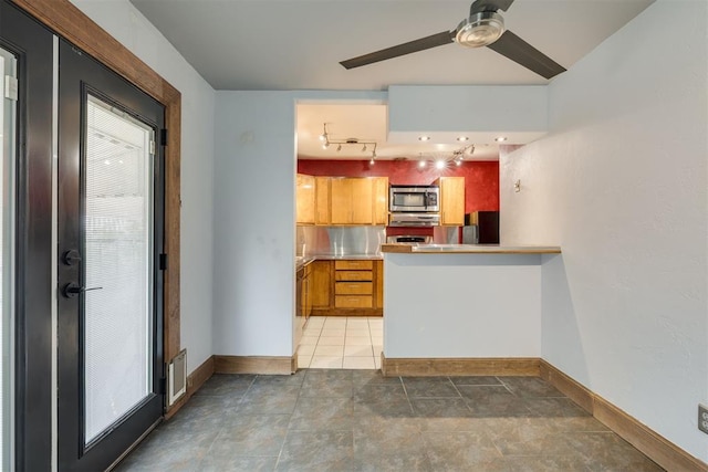 2527 NW 62nd St Unit 214, Oklahoma City, OK 73112 - kitchen with stainless steel microwave, freestanding refrigerator, ceiling fan, rail lighting, and light countertops