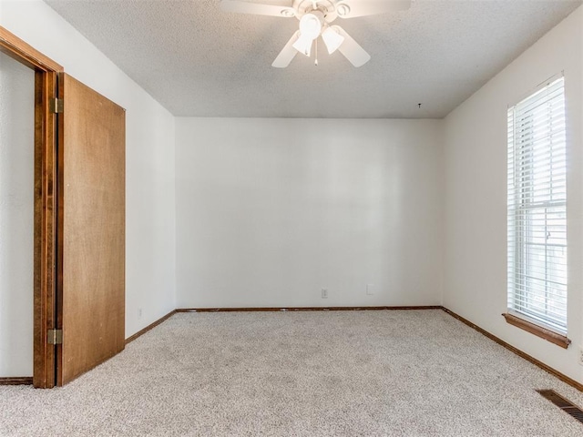 804 Royal Ln, Yukon, OK 73099 - unfurnished bedroom featuring multiple windows, carpet, a textured ceiling, and a ceiling fan