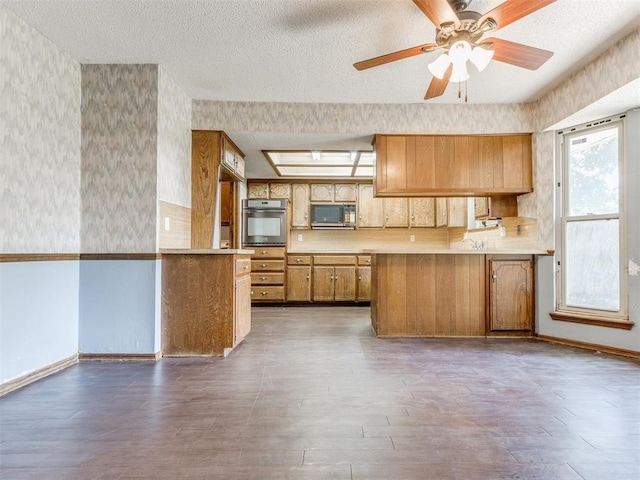 804 Royal Ln, Yukon, OK 73099 - kitchen with appliances with stainless steel finishes, a peninsula, light countertops, brown cabinets, and wood finished floors