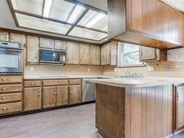 804 Royal Ln, Yukon, OK 73099 - kitchen with stainless steel appliances, light countertops, light wood-style flooring, and brown cabinets