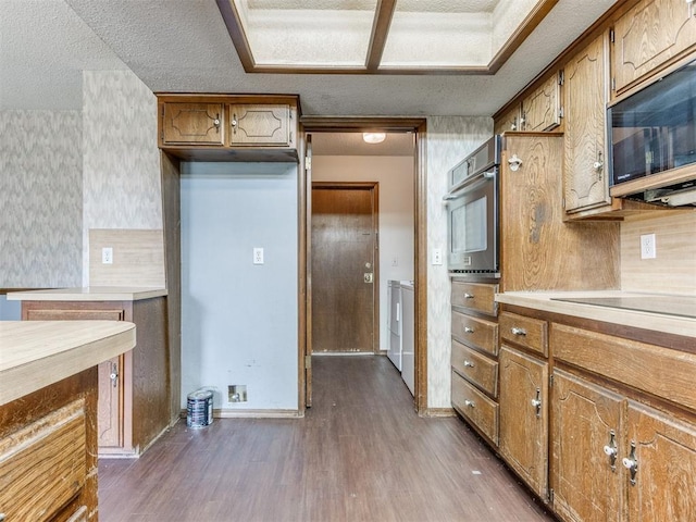 804 Royal Ln, Yukon, OK 73099 - kitchen with appliances with stainless steel finishes, dark wood-style flooring, washer and clothes dryer, brown cabinetry, and light countertops