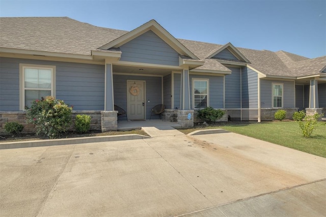 1010 SW 91st St, Oklahoma City, OK 73139 - view of front of property featuring a shingled roof, stone siding, a front lawn, and covered porch