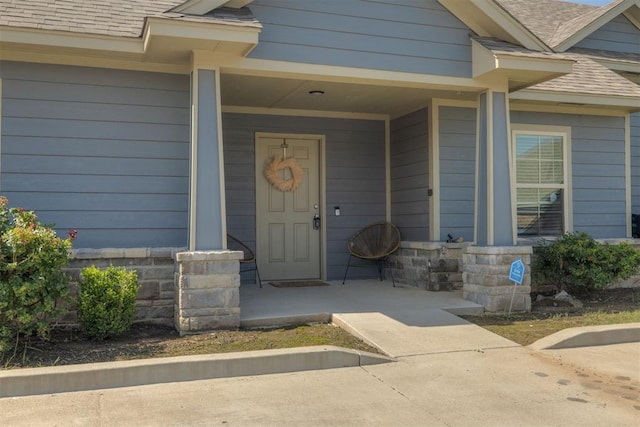 1010 SW 91st St, Oklahoma City, OK 73139 - doorway to property featuring a porch, a shingled roof, and stone siding