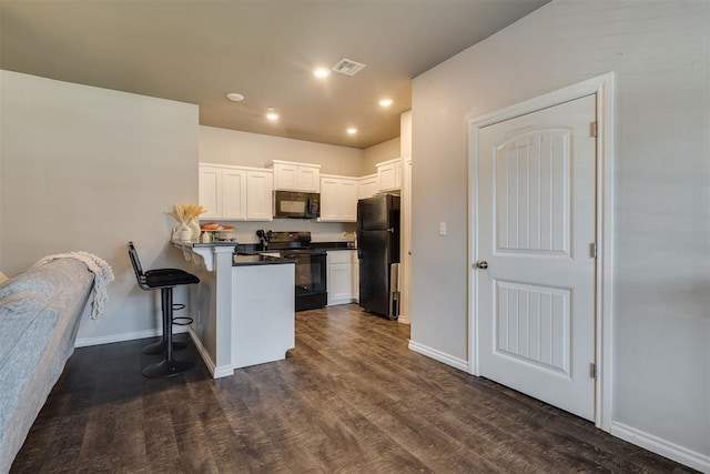 1010 SW 91st St, Oklahoma City, OK 73139 - kitchen featuring black appliances, a peninsula, a kitchen breakfast bar, white cabinets, and dark wood-style floors