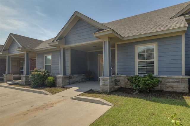 1010 SW 91st St, Oklahoma City, OK 73139 - view of front facade with a shingled roof, stone siding, a front lawn, and covered porch
