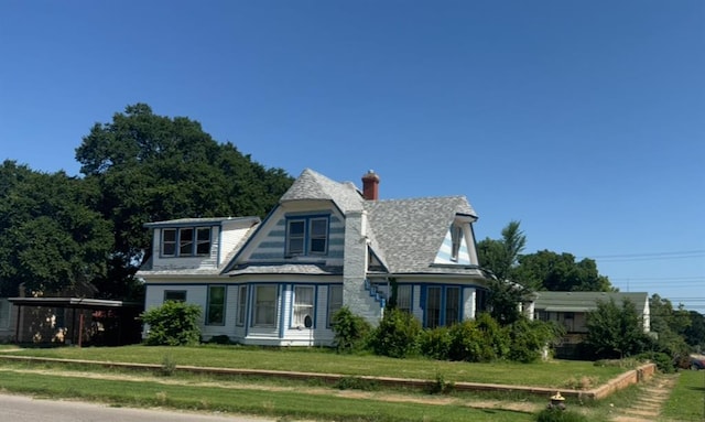 victorian house with a front yard and a chimney