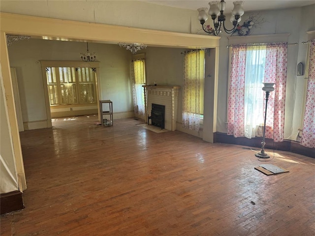 unfurnished living room featuring a chandelier, wood finished floors, and a fireplace