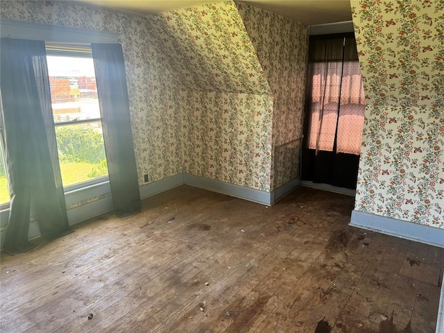 additional living space featuring wood-type flooring, wallpapered walls, and healthy amount of natural light