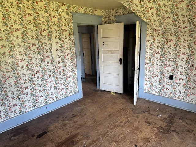 unfurnished room with wallpapered walls and wood finished floors