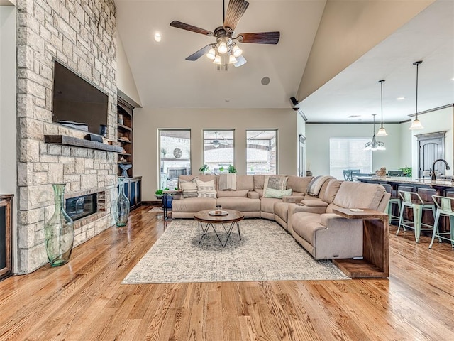 4311 Moorgate Dr, Norman, OK 73072 - living room with a stone fireplace, a ceiling fan, wood finished floors, high vaulted ceiling, and recessed lighting