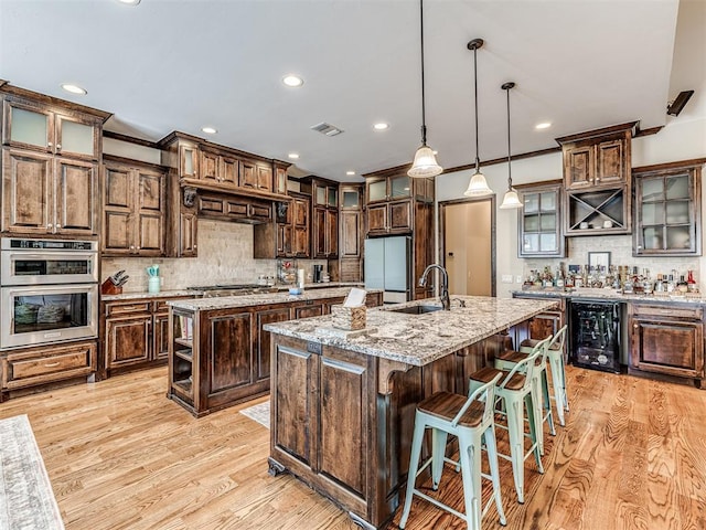 4311 Moorgate Dr, Norman, OK 73072 - kitchen featuring an island with sink, stainless steel appliances, wine cooler, decorative backsplash, and recessed lighting