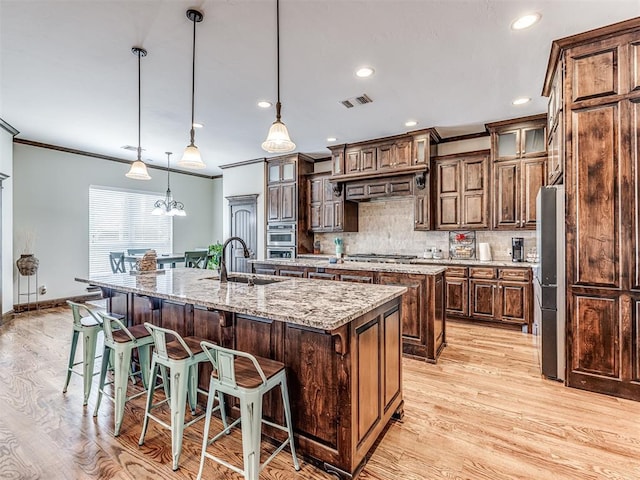 4311 Moorgate Dr, Norman, OK 73072 - kitchen featuring a large island with sink, stainless steel appliances, light wood-type flooring, a kitchen bar, and ornamental molding