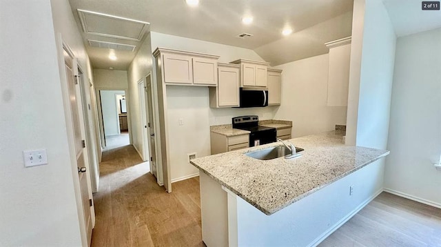 1614 SW C Ave, Lawton, OK 73501 - kitchen featuring appliances with stainless steel finishes, a peninsula, light wood-style flooring, light stone counters, and lofted ceiling