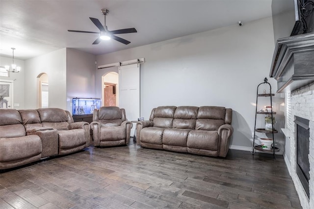 3309 Austrian Pine Ln, Yukon, OK 73099 - living area with a barn door, dark wood-style floors, a fireplace, a ceiling fan, and arched walkways