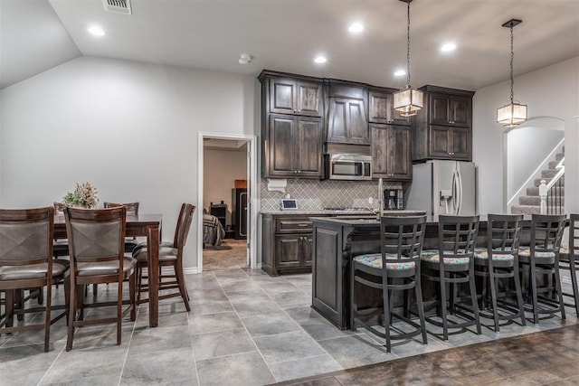3309 Austrian Pine Ln, Yukon, OK 73099 - kitchen with stainless steel appliances, a breakfast bar area, dark brown cabinets, tasteful backsplash, and recessed lighting