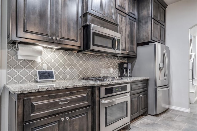 3309 Austrian Pine Ln, Yukon, OK 73099 - kitchen with stainless steel appliances, tasteful backsplash, dark brown cabinets, light stone counters, and arched walkways