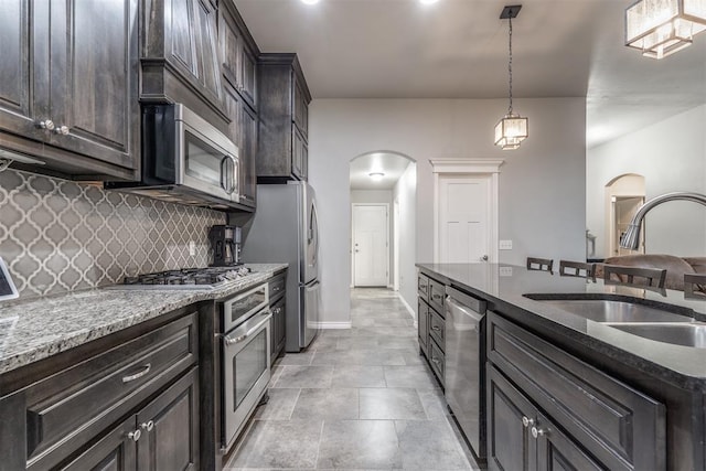3309 Austrian Pine Ln, Yukon, OK 73099 - kitchen featuring arched walkways, stainless steel appliances, backsplash, dark brown cabinets, and dark stone counters