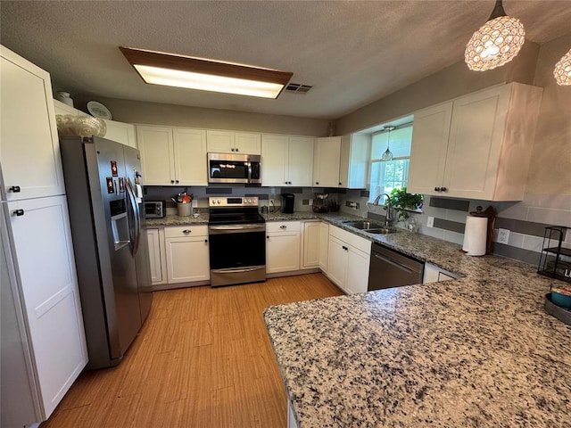 35352 Ew 1260th Rd, Seminole, OK 74868 - kitchen featuring appliances with stainless steel finishes, light wood-type flooring, white cabinetry, stone countertops, and a textured ceiling