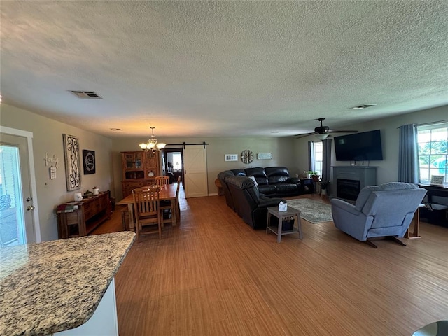 35352 Ew 1260th Rd, Seminole, OK 74868 - living area featuring a chandelier, wood finished floors, a textured ceiling, a fireplace, and ceiling fan