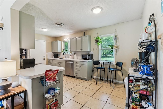 709 W Hughbert St, Norman, OK 73069 - kitchen featuring stainless steel appliances, a textured ceiling, light countertops, healthy amount of natural light, and light tile patterned flooring
